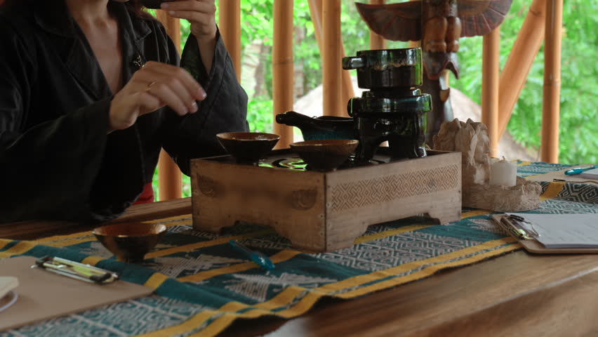 The hands making a tea ceremony on the wooden table before the start of the gong ceremony in a gazebo