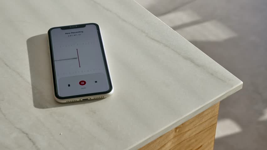 Smart mobile phone on kitchen counter recording conversation with voice notes app. Close up on cellphone with recording application listening to person talking capturing sound waves in apartment room