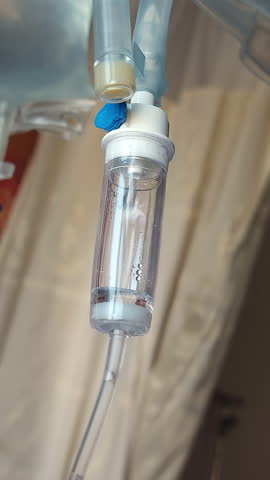 Saline solution is dripped into a metal hook hanging on the wall in the hospital.
