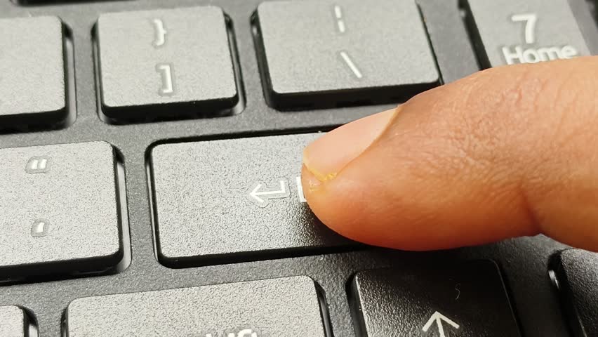 Close up macro top view of finger pressing laptop enter button on keyboard. Digital confirmation, sending email message, online office work and input data concept.