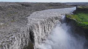Aerial view of Dettifoss waterfall in Iceland, showcasing dynamic water motion, mist filled gorge, green moss, and rugged rocky terrain. - Powered by Shutterstock - Get 15% off with code: PIKWIZARD15