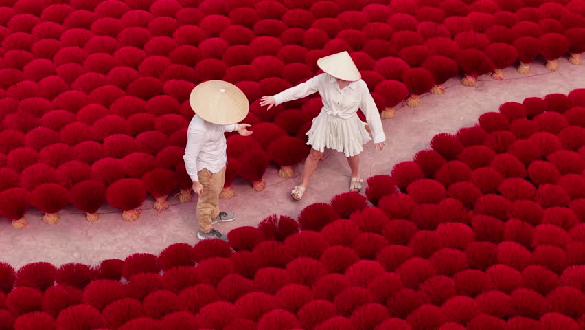 Trip of Lover couple in Viet, two tourists are walking on traditional aroma red incense production Vietnam Aerial view.