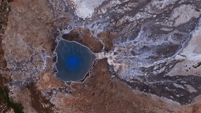 Aerial view of a vibrant blue geothermal hot spring in Iceland, surrounded by white and brown mineral deposits, with steam rising and sparse vegetation. - Powered by Shutterstock - Get 15% off with code: PIKWIZARD15