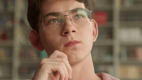 Close up hesitate Caucasian teenager guy pensive holding chin thinking decision solution difficult ponder choosing book in school college library teen boy think thoughtful education studying learning - Powered by Shutterstock - Get 15% off with code: PIKWIZARD15