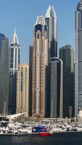 Dubai, home to a striking collection of modern skyscrapers, famed for their architectural beauty, set against the backdrop of a vast marina with luxury yachts, vertical video, no logos