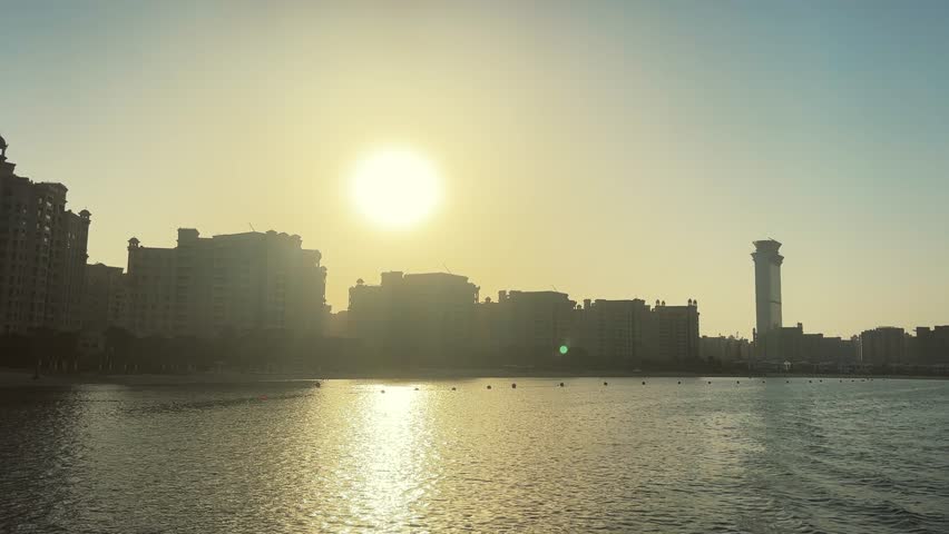 Summer beach sunset over Jumeirah Palm buildings in Dubai, UAE, no logos