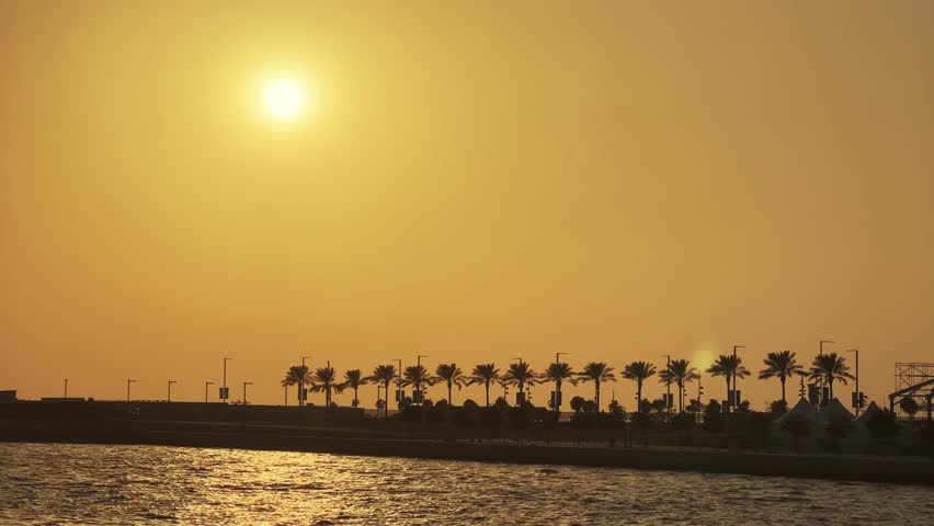 Luxury tourist yacht depart sailing from Dubai Marina port with view of Jumeirah beach at background at sunset
