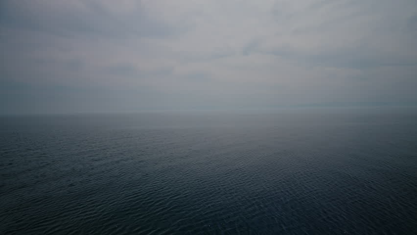 Panoramic view of calm waters of lake Baikal rippling under cloudy sky during peaceful boat trip, creating serene and expansive landscape embodies beauty of nature in Siberia. Shooting in slow motion.