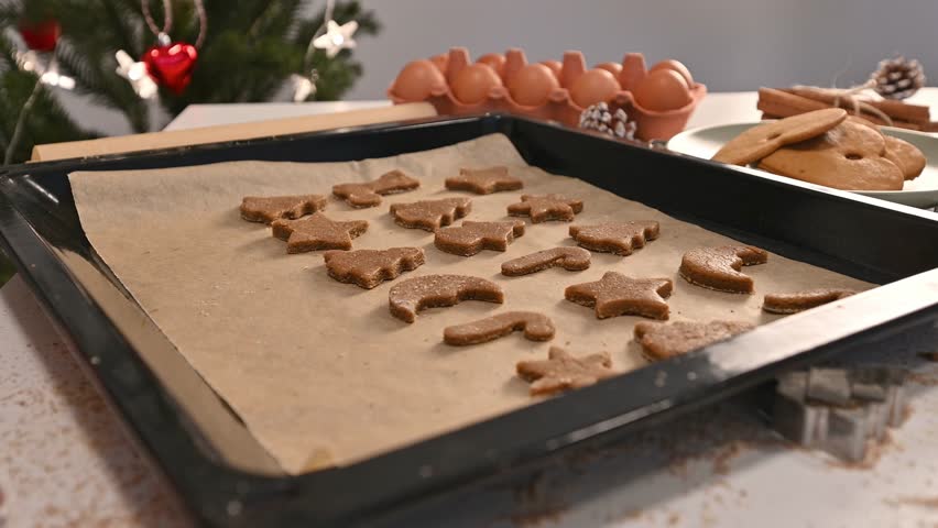 Womans puts gingerbread christmas cookies on a baking tray 