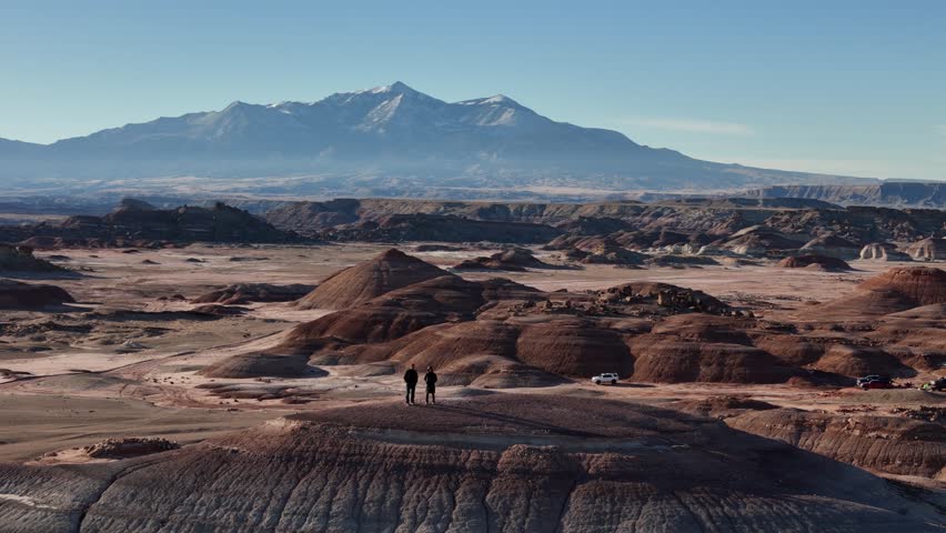 Orbiting Drone Shot of Two People Standing on Top of Hill in Desert Landscape of Utah USA, Bentonite Hills