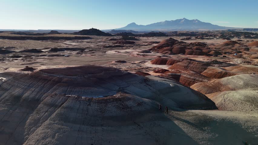 Drone Shot of Two People Walking Uphill in Landscape of Bentonite Hills, Utah USA