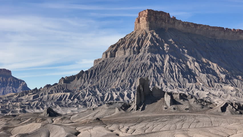 Drone Shot of Black Vehicle Moving Under Gray Sandstone Formations in Desert Landscape of Utah USA