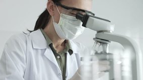 Female scientist examining microscope slide, wearing protective gear while conducting medical research in sterile laboratory environment. Medicine, healthcare and science concept - Powered by Shutterstock - Get 15% off with code: PIKWIZARD15