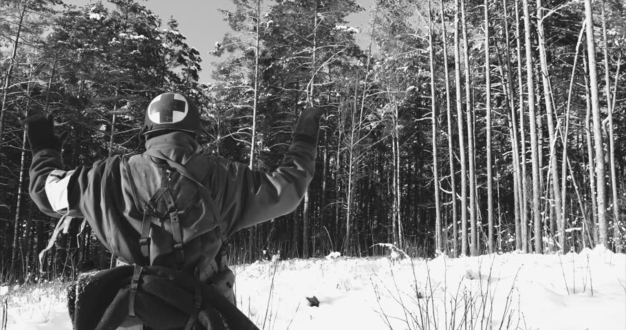 Historical Re-enactment Black And White Video. 4K Re-enactor Dressed As American Soldier Medic Of USA Infantry Of World War II Come Out Of Ambush With Hands Up Surrender To Captivity In Winter Day.