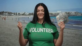 Woman volunteer smiling on sunny beach holds us dollars, conveying trust and community spirit in serene seaside setting. - Powered by Shutterstock - Get 15% off with code: PIKWIZARD15