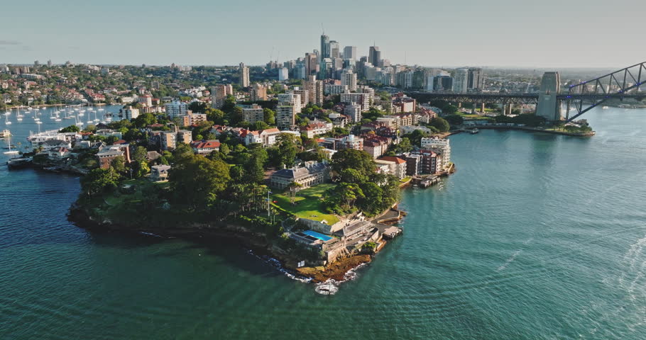 Australia, Sydney: Kirribilli suburb with lush greenery, elegant homes houses, and iconic Sydney Harbour Bridge gracing the horizon. Modern cityscape architecture. Drone flight aerial view footage
