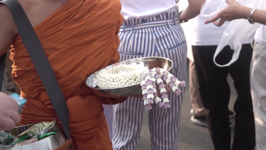 People make merit by giving food and goods to Buddhist monks.