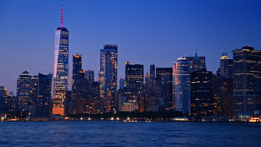 Stunning night skyline of New York, USA. Riverboats travel by the river enjoying the beautiful city.