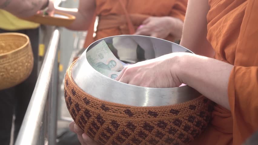 People make merit by giving food and goods to Buddhist monks.