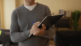 Man writing on clipboard in an office setting with soft lighting and blurred background focusing on workspace elements. - Powered by Shutterstock - Get 15% off with code: PIKWIZARD15