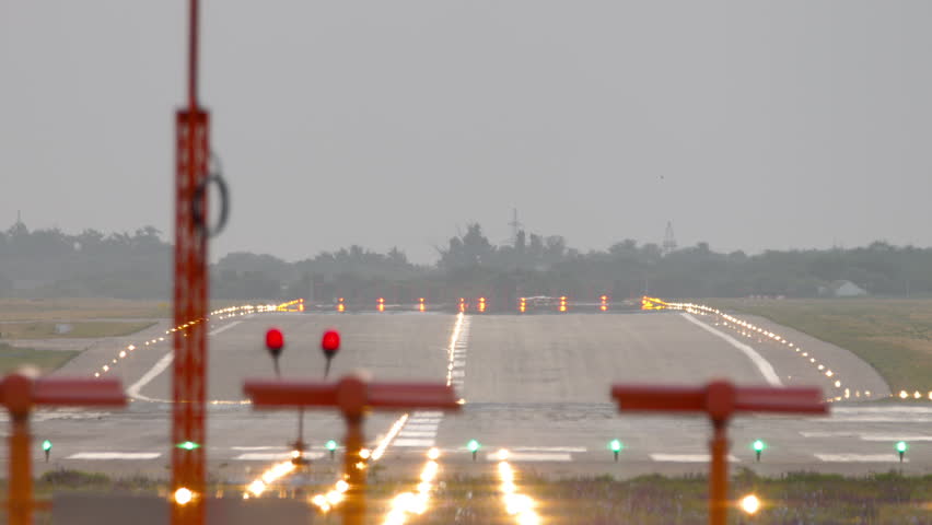 End view of an empty airport runway illuminated with landing lights. Aviation scene perfect for travel, transportation, and airport themes