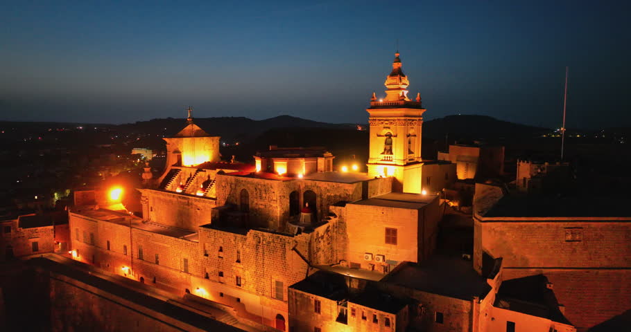 Malta, Comino island: Citadel of Victoria in Gozo create a captivating dusk scene reflecting Maltese history and majestic architecture and surrounding landscape at night. Drone flight panorama