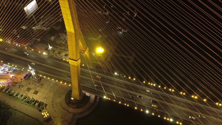 Aerial view of illuminated Rama VIII Bridge at night. Cable-stayed bridge crossing Chao Phraya River in Bangkok, Thailand, 4k