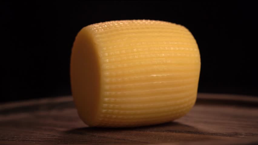 Smoked cheese wheel rotating on wooden board