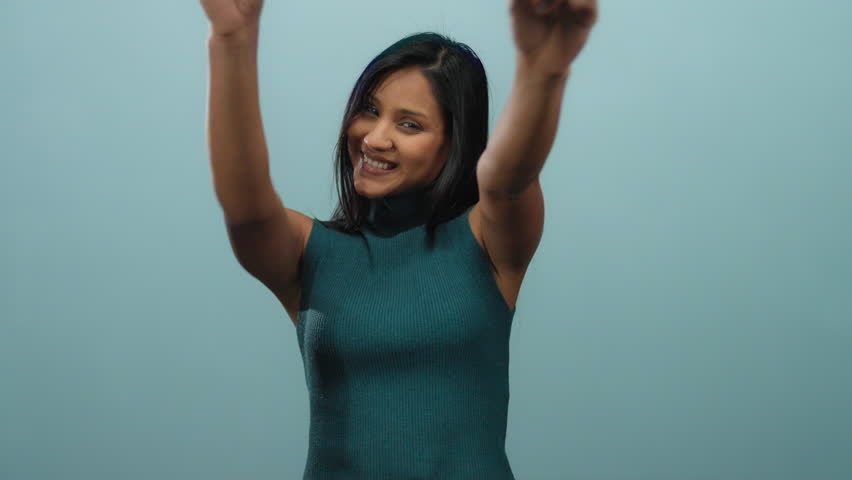 Woman making victory gesture with fingers while smiling on isolated blue background