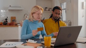 Young multi ethnic couple paying bills and shopping online using laptop and credit card, managing home finances together - Powered by Shutterstock - Get 15% off with code: PIKWIZARD15