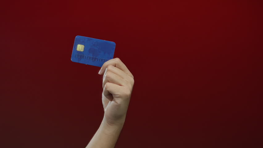Man holding credit card against red background showcasing isolated financial concept with caucasian male hand prominently featured for business illustrations
