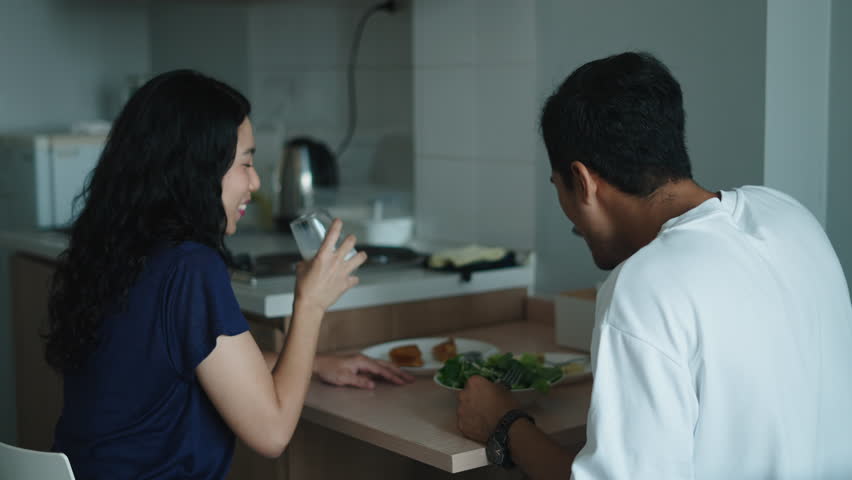 Young asian couple preparing nutritious meal, talking together in contemporary kitchen space