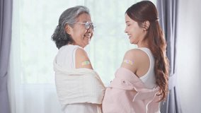 Asian Elderly woman and young woman indoors smiling happily with colorful bandages on upper arms after vaccination showing health, protection, happiness, and family care in bright room with curtains - Powered by Shutterstock - Get 15% off with code: PIKWIZARD15