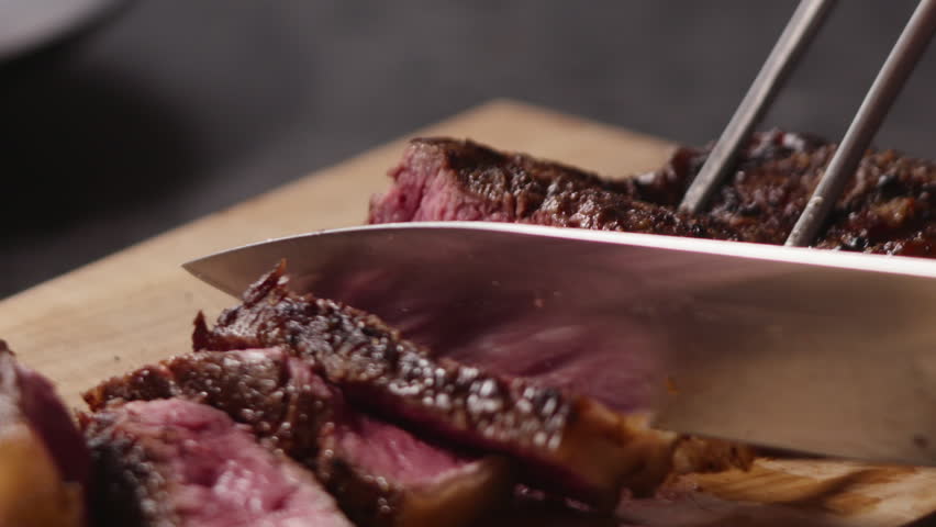 Slow motion slicing new york steak closeup soft vintage look