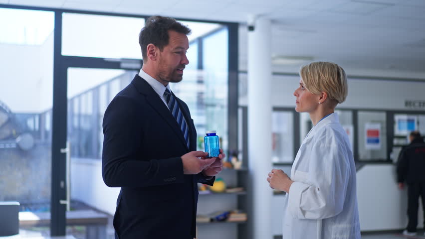 Pharmaceutical sales representative introducing new medication to female doctor.