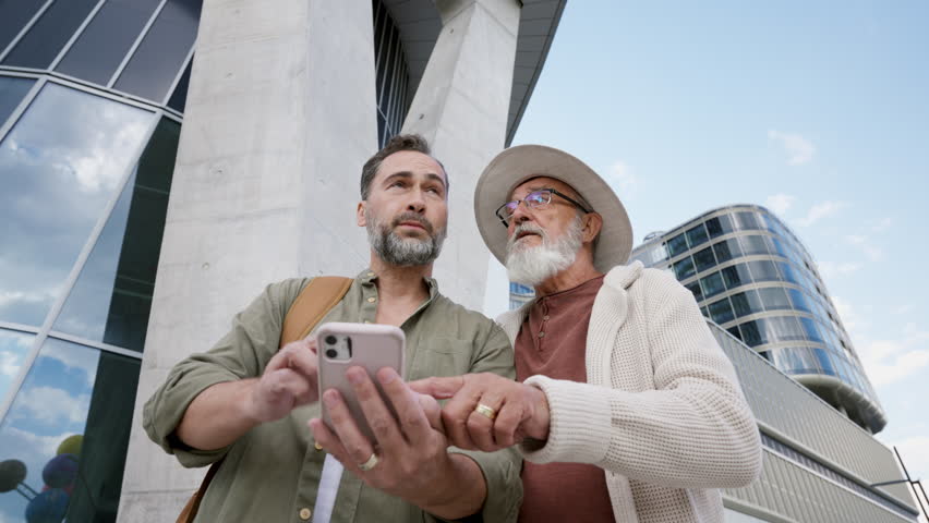 Father and son looking for directions on smartphone, sharing a joyful moment.
