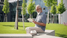 Senior man reading newspapers and writing something down in city park. - Powered by Shutterstock - Get 15% off with code: PIKWIZARD15