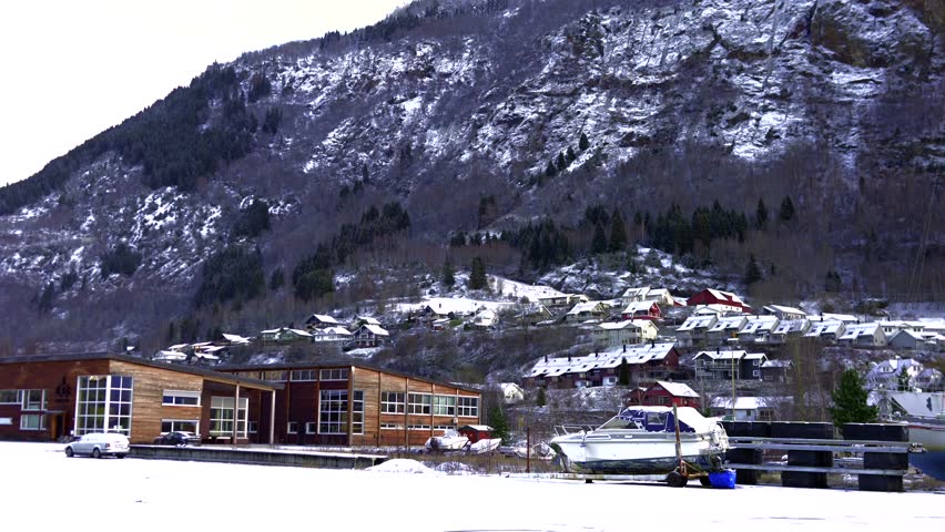 Snowy hillside houses along fjord with distant mountains Gaupne Norway