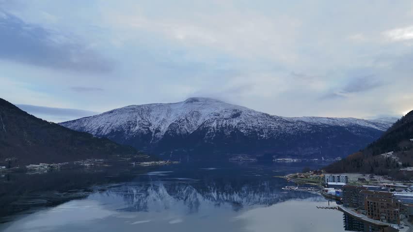 Aerial view of winding coastal road along snowy Norwegian fjord