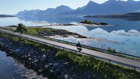 Beautiful drone shot of a coastal landscape on Engeløya island, showing cyclists, blue sea, mountains, and peaceful Nordic nature in the morning light - Powered by Shutterstock - Get 15% off with code: PIKWIZARD15