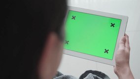 A person interacts with a green screen displayed on a tablet. The green background is designed for video editing or special effects, highlighting modern technology's role in creative processes. - Powered by Shutterstock - Get 15% off with code: PIKWIZARD15