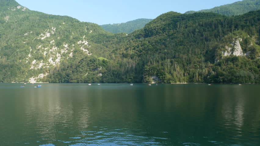 Pedal boats and canoes on the mountain lake, weekend at the lake