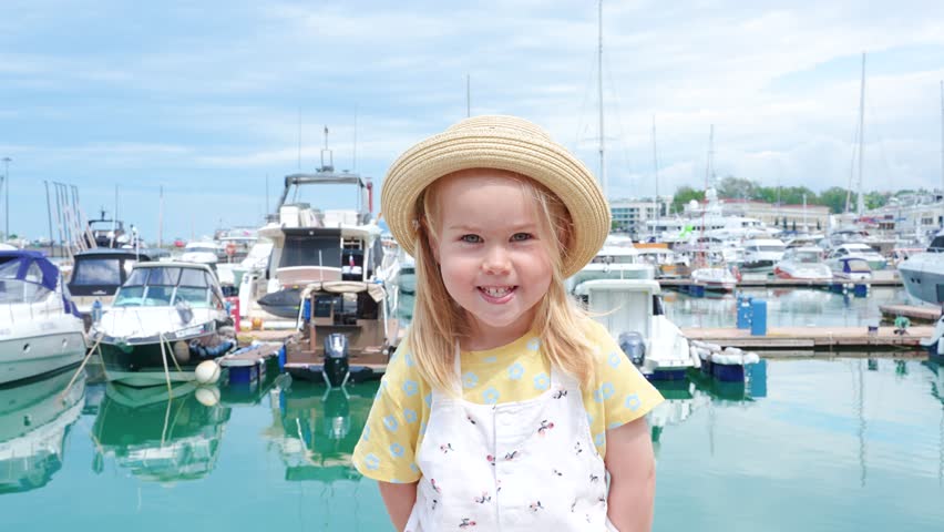 portrait of happy caucasian girl child at a Beautiful marine station with yachts and ships