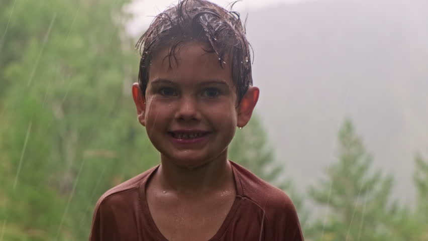 Smiling child enjoying the rain in a mountain landscape