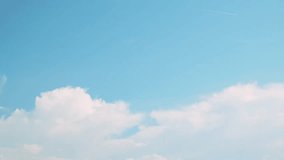 Cumulus clouds floating in the blue sky and an airplane flying high in the sky and contrails. Background material for summer skies. Panning from right to left. - Powered by Shutterstock - Get 15% off with code: PIKWIZARD15