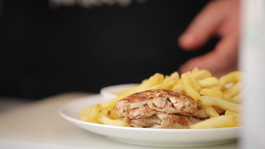 A chef prepares a delicious fast food shawarma wrap on a hot griddle. The meat and tortilla sizzle and brown, a mouth-watering process for the hungry.