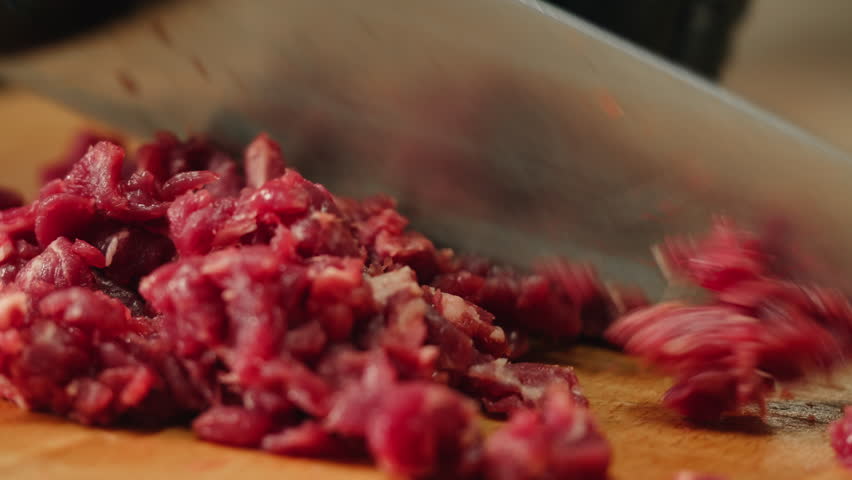 Working with beef, cut steak Chef cooking Raw beef meat tartar with sauce, man cutting steak tartare, making delicious french dish in modern restaurant. Fresh eco angus meat. 