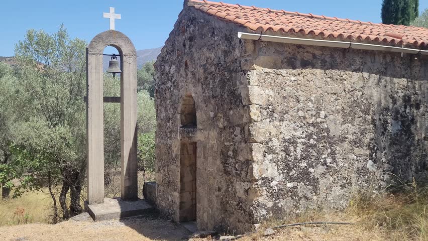 Small Orthodox chapel with a bell among olive trees on the island of Crete