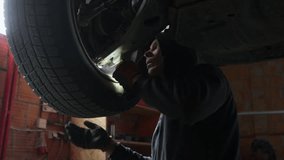 Auto mechanic visually inspects wheel play with a flashlight to diagnose a problem. Technician examines the car suspension and worn ball joint, checking for wobble on a lifted vehicle in a garage. - Powered by Shutterstock - Get 15% off with code: PIKWIZARD15