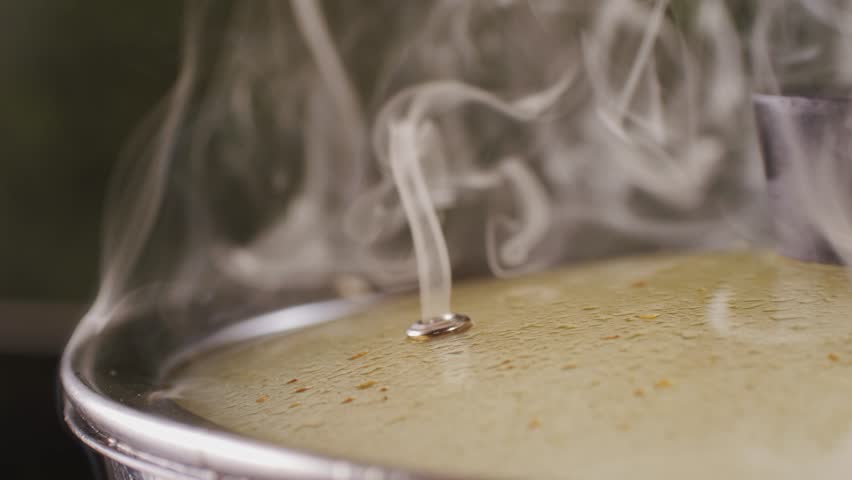 Stainless steel pot on a gas stove with boiling water and steam, cooking soup